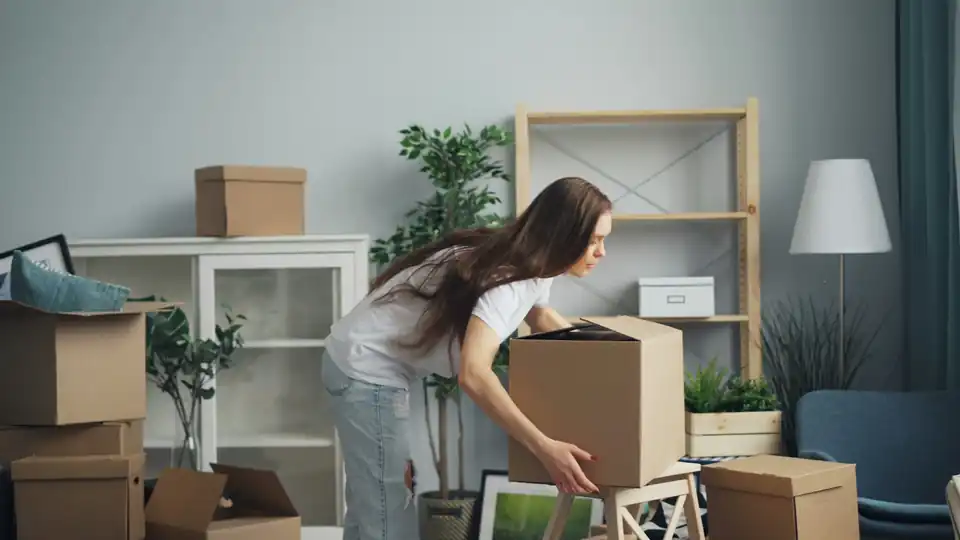 Person unpacking moving boxes in a bright room