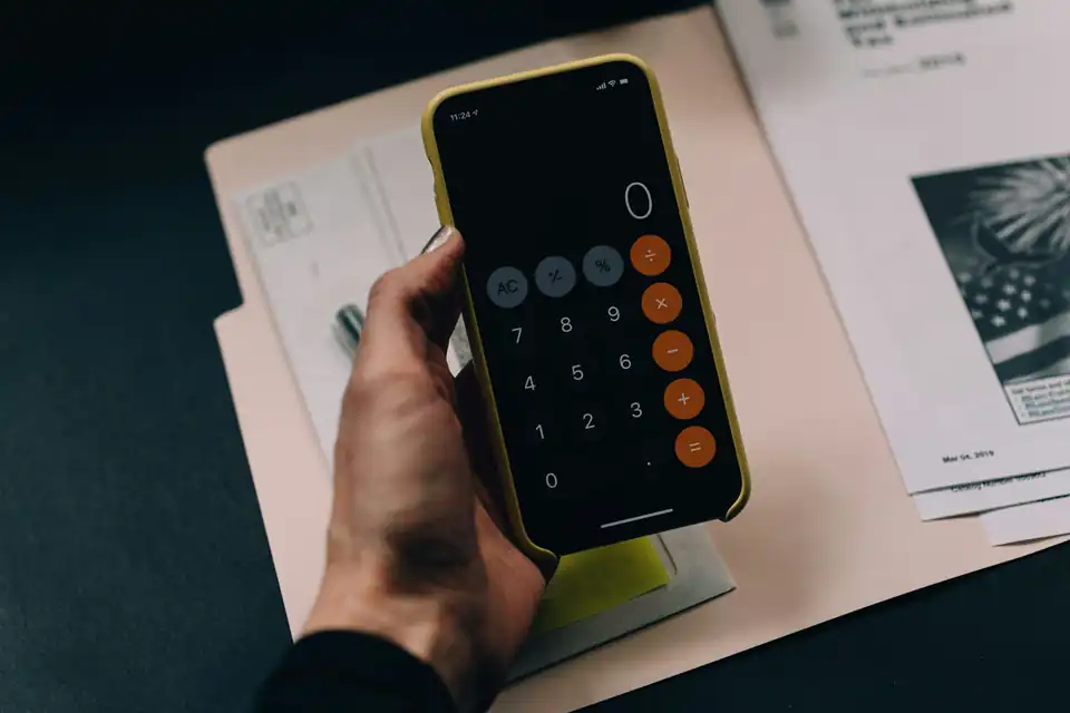 Hand holding a phone calculator over documents