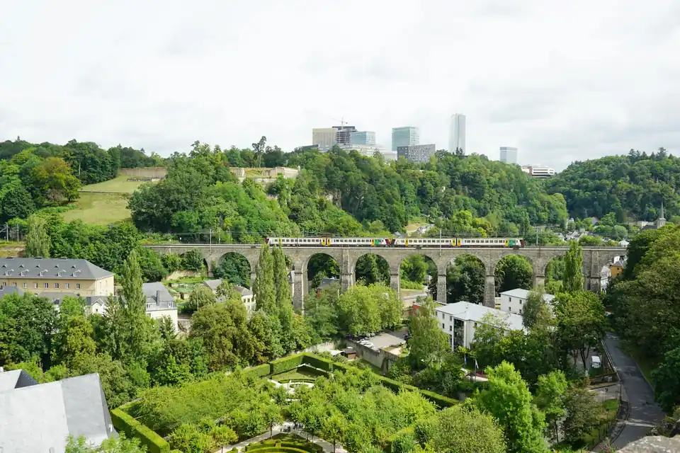 Train on a stone viaduct over the Alzette valley with Kirchberg towers behind