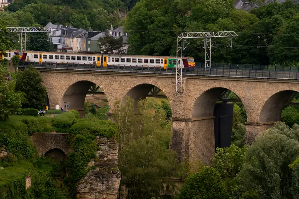 Train crossing a stone viaduct above woodland in Luxembourg City
